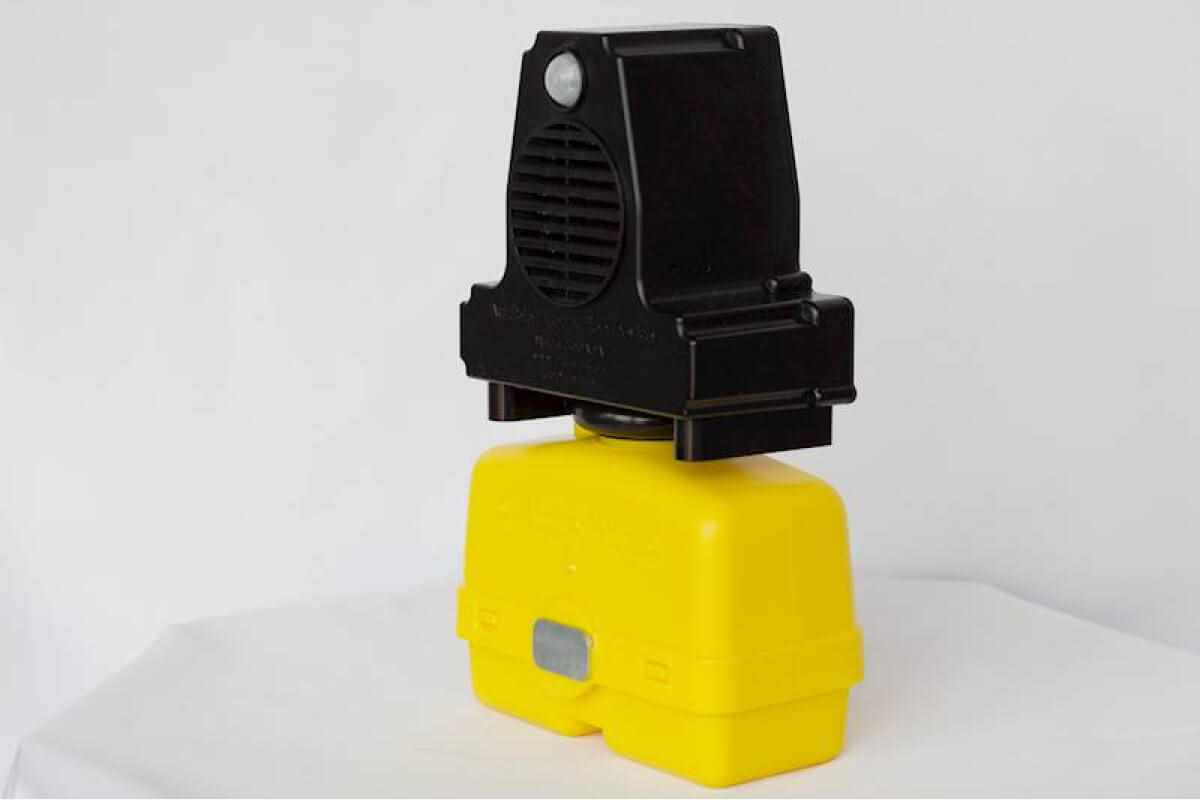 Portable construction warning siren with a black speaker unit mounted on a yellow battery base, used for safety alerts in work zones.